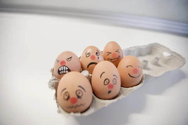 Seis huevos con rostros pintados en un cartón de huevos — Foto ...