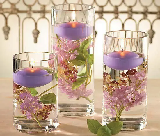 velas flotantes en cilindros de vidrio con flores frescas y agua ...