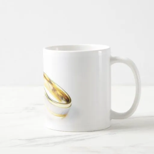 Anillos de bodas de oro en el fondo blanco taza de Zazzle.