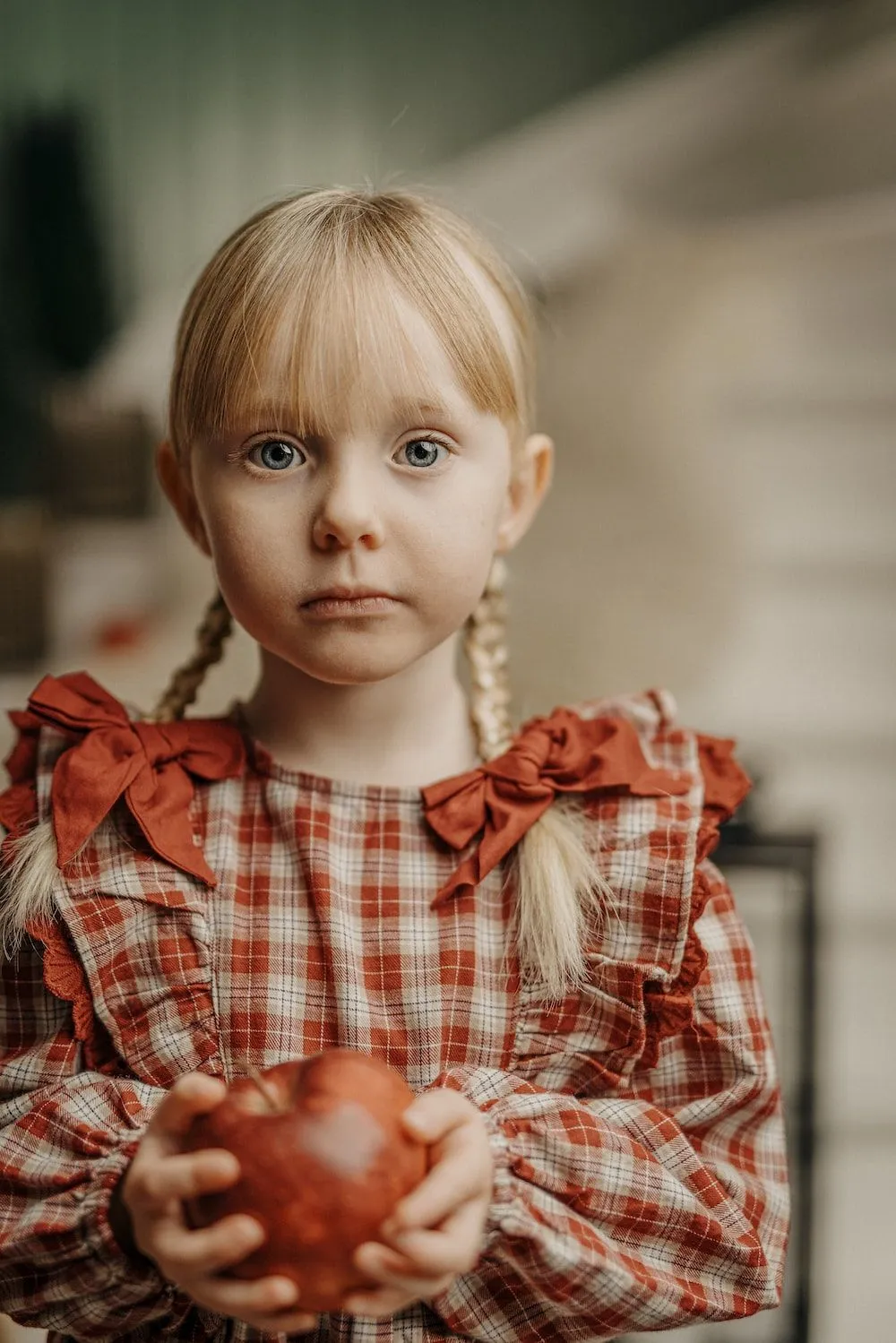 Foto Una niña sosteniendo una manzana con una mirada triste en su rostro – Imagen Navidad gratis en Unsplash
