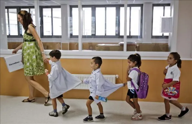 Un grupo de niños en fila se dirigen a clase con la profesora al ...