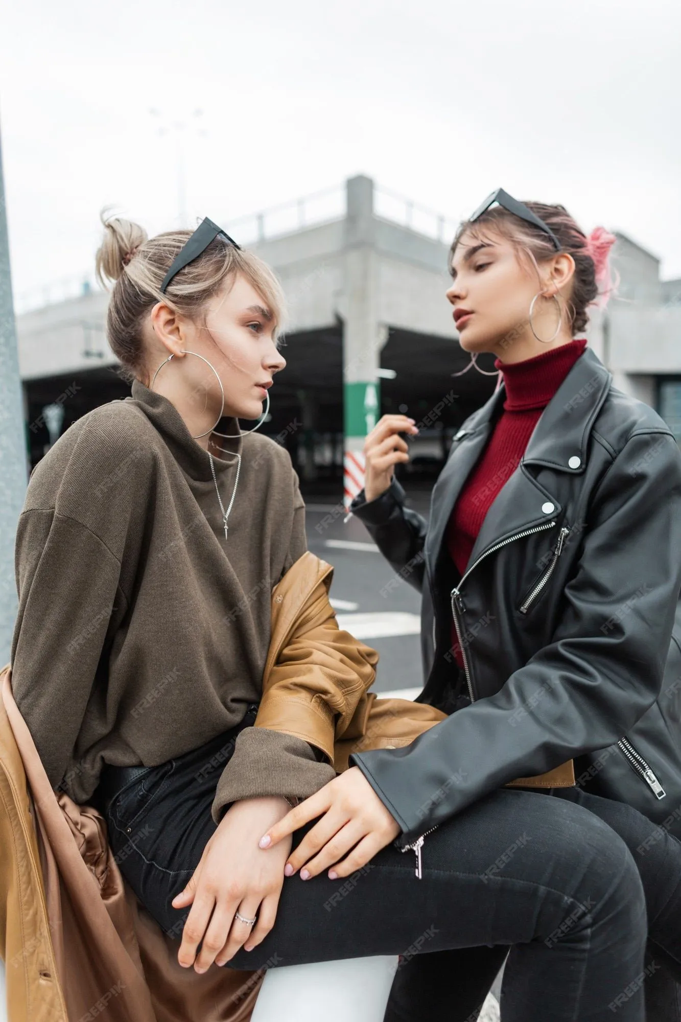 Hermosas jovencitas en ropa de moda se sientan en la calle de la ciudad |  Foto Premium