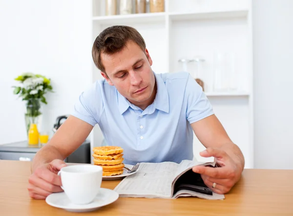 hombre concentrado leyendo un periódico desayunando — Foto stock ...