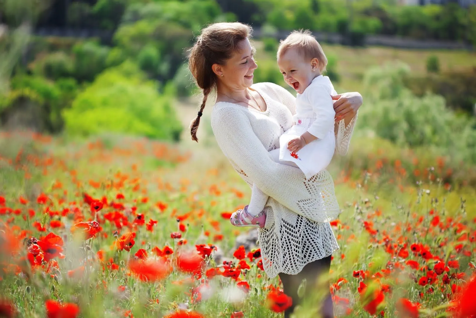 Mujer bonita paseando a su bebé por los campos cubiertos de flores ...