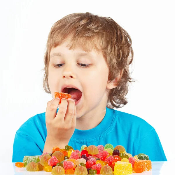 niño comiendo caramelos de la jalea sobre fondo blanco — Foto ...