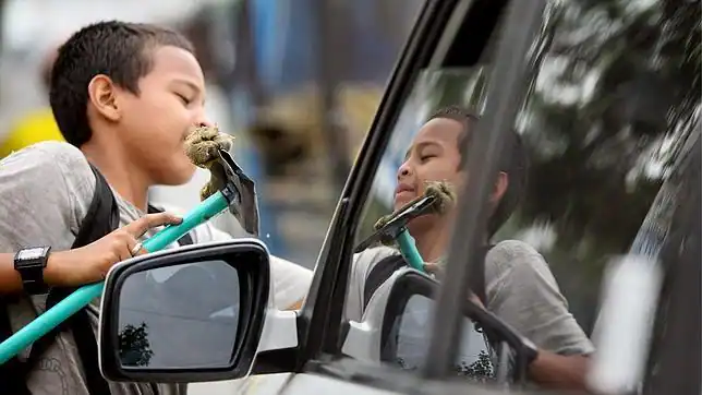 Un niño trabaja limpiando los vidrios de las automóviles en Cali ...