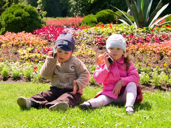 niño y niña jugando en el parque con los teléfonos móviles — Foto ...