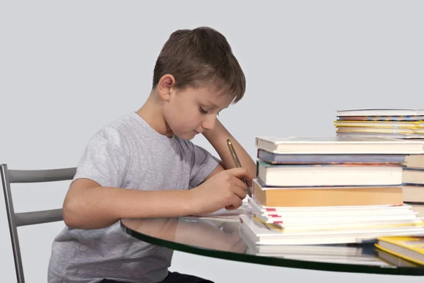 niño hace su tarea con una pluma en la mano — Foto stock © Afonco ...