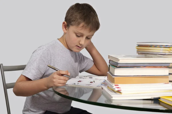 niño hace su tarea con pluma en mano en media vuelta — Foto stock ...